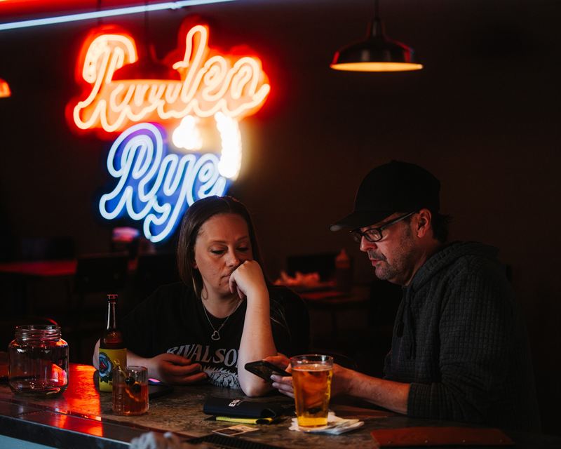 Guests hanging out at a table under the neon at Rodeo & Rye